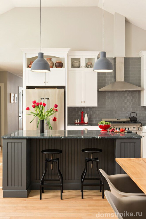 Серый кухонный гарнитур, серые лампы, металлическая бытовая техника скомпонованные с ярко-красными кухонными аксессуарами