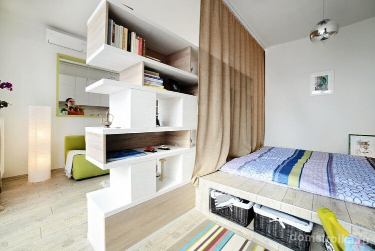 Современная квартира-студия, в которой полочки выступают в роли перегородки между двумя основными зонами жилища