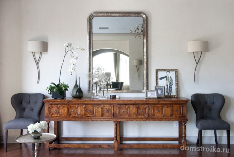 Состаренное зеркало и роскошный деревянный комод ручной работы смотрятся очень гармонично