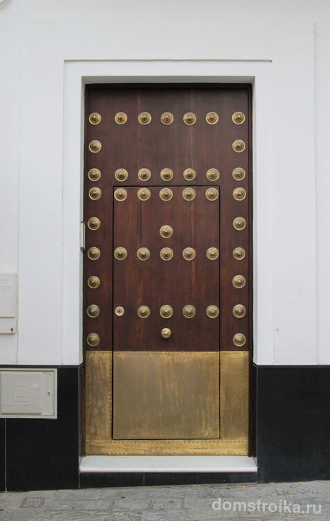 Деревянная входная дверь декорированная медными заклепками