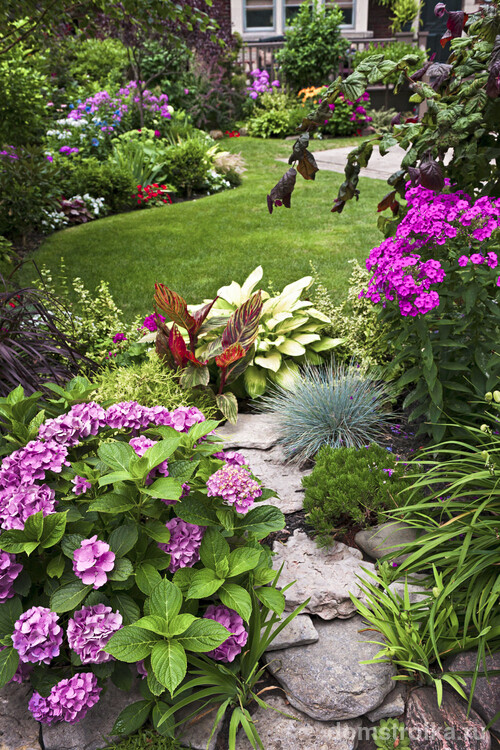 Аккуратно сложенные камни в форме полукруга в композиции с цветущими растениями - эффектна клубма у вас во дворе