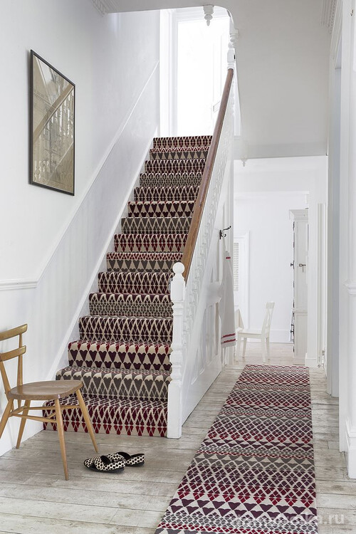 Ковровые дорожки с одинаковым принтом удачно декорируют лестницу и белоснежный коридор