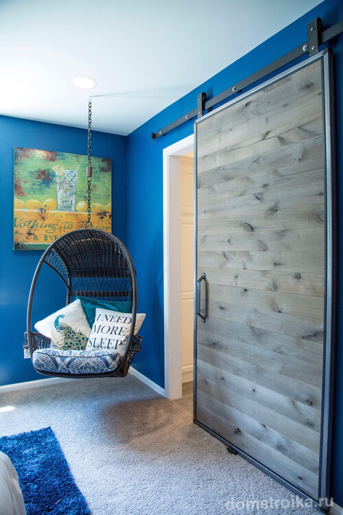 Дверь-купе с полотном из сероватого дерева отлично гармонирует с ярким синим цветом стен комнаты