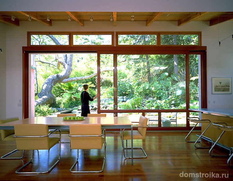 Огромные двери-купе из натурального дерева и стекла в частном загородном доме и вравду создают ощущение настоящего необъятного простора