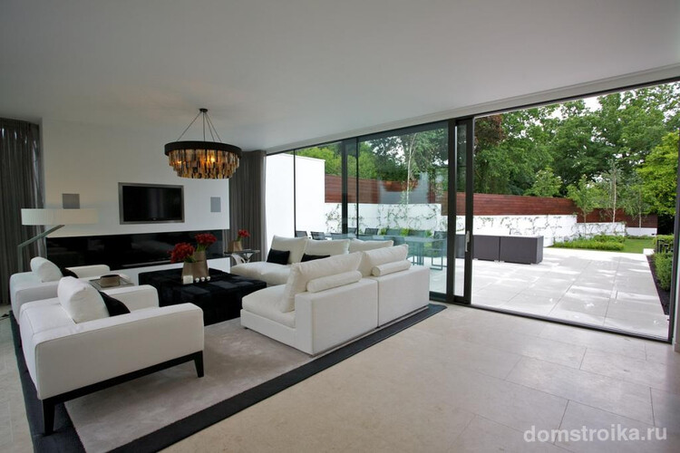 Большие стеклянные двери-купе в частном доме, отлично гармонируют с общим интерьером просторной гостиной