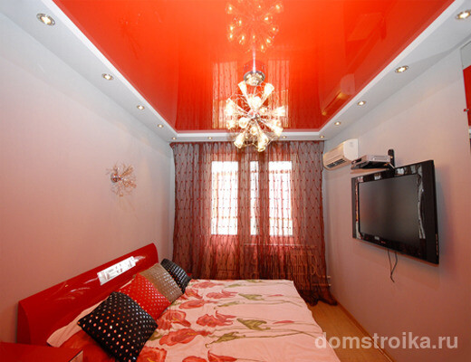 Ярко-красный глянец потолка, гармонирующий с изголовьем кровати, не выглядит агрессивно благодаря белым стенам