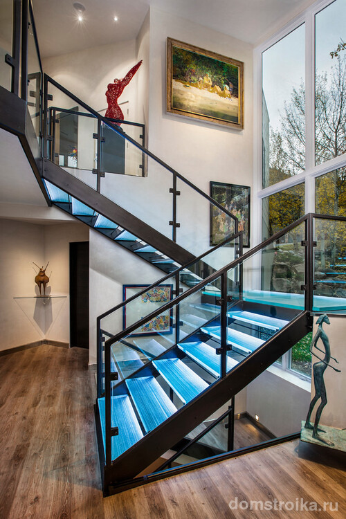 Трехмаршевая стеклянная лестница с подсветкой ступеней и металлическими перилами никогда не будет смотреться скучно
