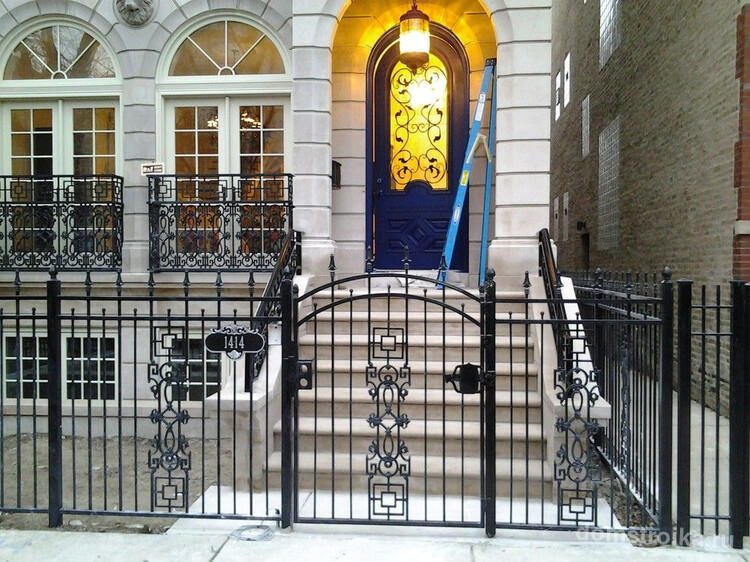 Кованый забор гармонично сочетается с такими же ограждениями на окнах и коваными элементами дверей