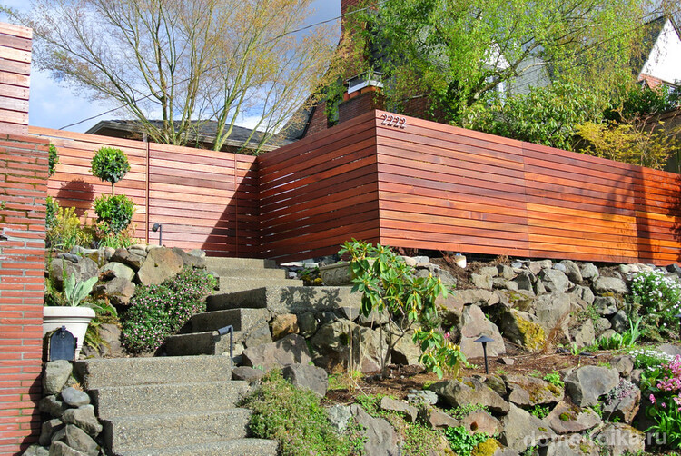Придомовая территория с ландшафтным дизайном украшена красивым деревянным забором