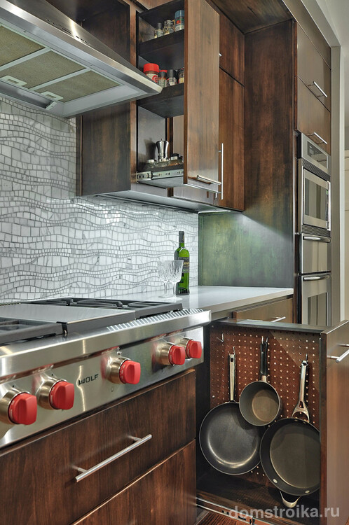 Хранить кухонные принадлежности удобно в подвешенному виде в узкой выдвижной ячейке возле плиты