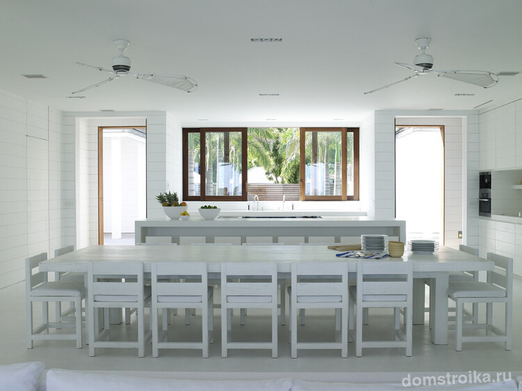 Массивный стол для большого количества гостей замечательно смотрится в современной кухне