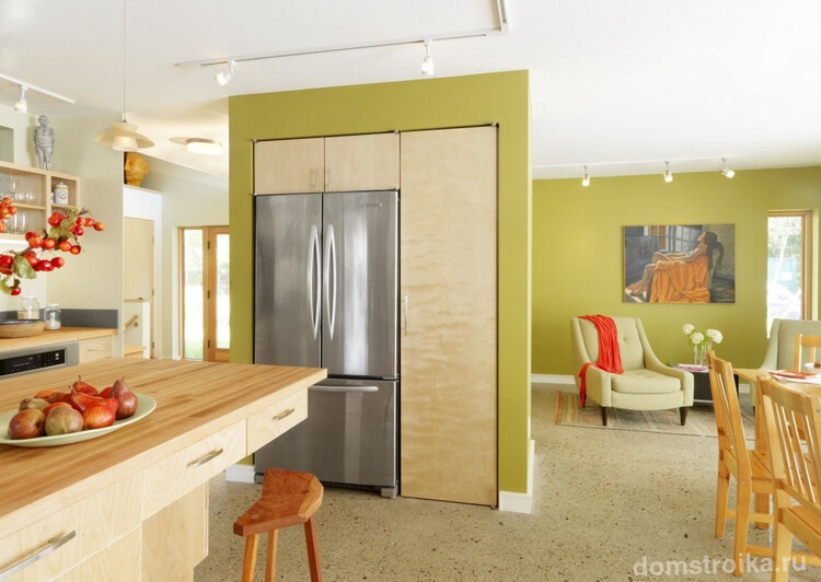 В квартире-студии холодильник, встроенный в небольшую стену, не только обеспечивает комфортность пребывания на кухне, но и служит элементом зонирования помещения