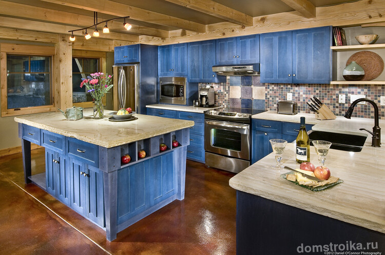 Дизайн кухни выполненный в дереве с крашеными фасадами в приятный синий цвет - необычное решение. Холодильник занял свое место в углу возле окна