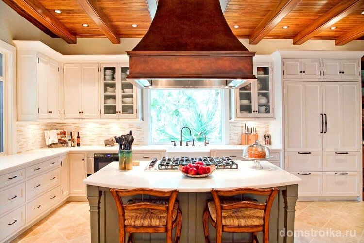 Большая деревянная вытяжка на встроенной кухне станет ярким элементом на фоне белой мебели