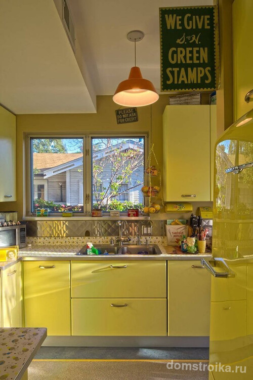 Яркий холодильник сочного оливкового цвета на небольшой кухне частного дома