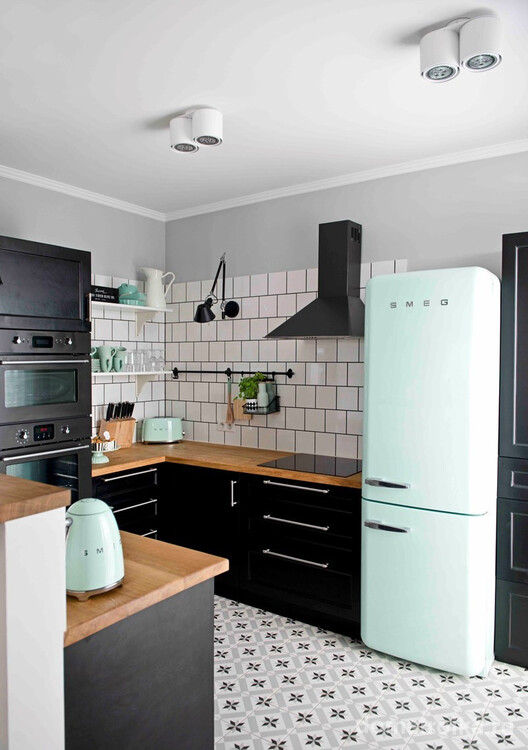 Большой фирменный холодильник марки Smeg на кухне в черно-белых мотивах с элементами гарнитура из натурального дерева