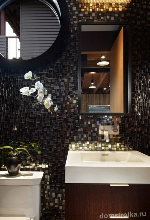 Цветная стеклянная плитка в декоре темной ванной комнаты может быть разбавлена белыми элементами в виде раковины или цветов
