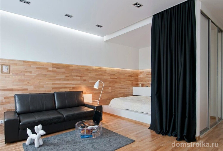 Красивые черные шторы из плотной ткани отделяют спальное место от зоны гостиной