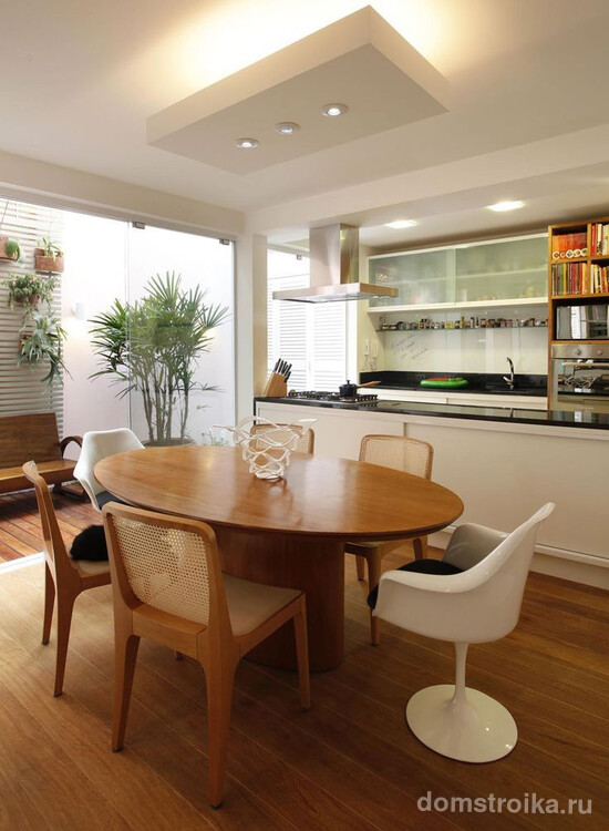 Овальный стол на кухне гостиной разделяет зону приготовления пищи и отдыха