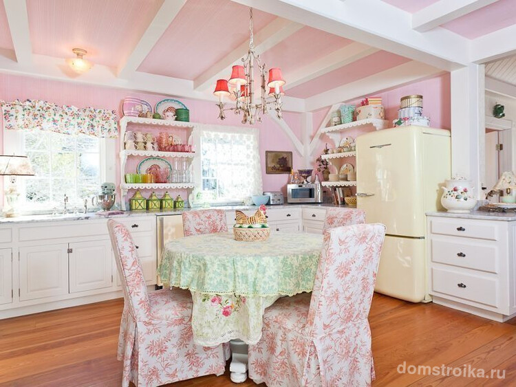 Кухня в стиле шебби-шик: розовая отделка стен и потолка, люстра, цветастые чехлы на стульях и бежевый кухонный гарнитур