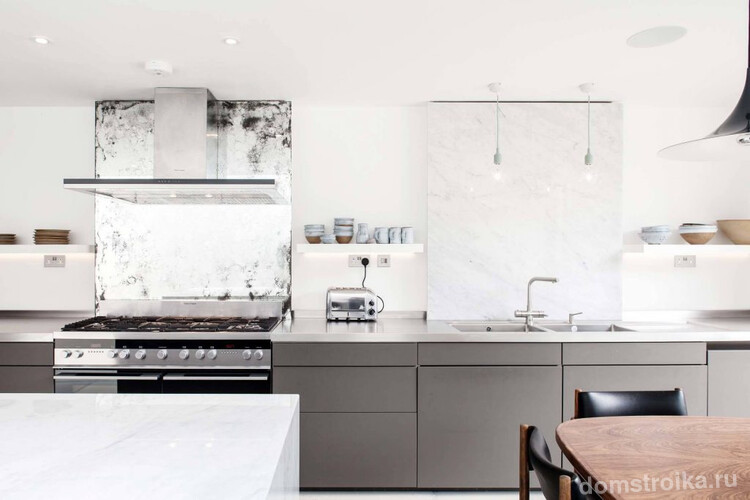 Кухня без верхних шкафов: серые матовые фасады в сочетании с гладкими поверхностями, имитирующими антикварное зеркало и белый мрамор