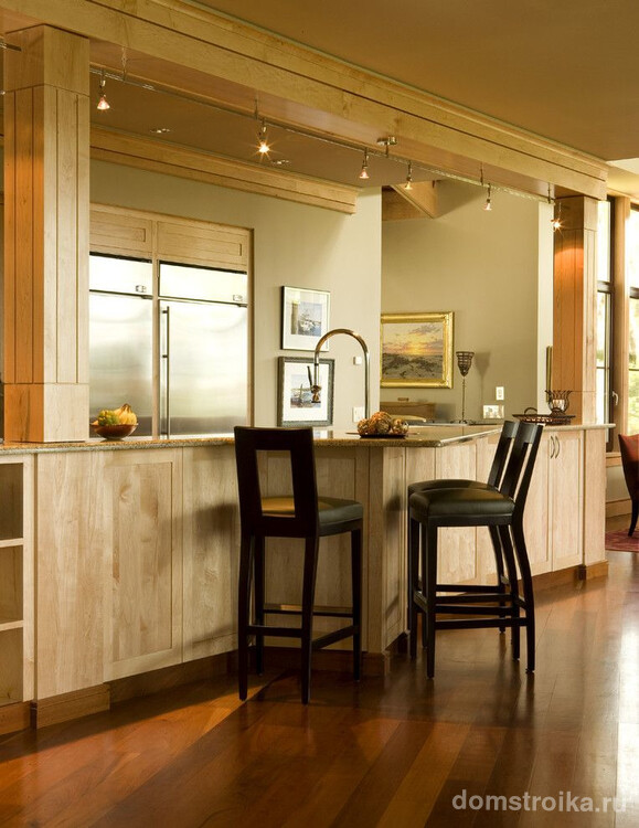 Объединенная с кухонным гарнитуром барная стойка на современной кухне. Шинная система освещения со светильниками с поворотной функцией, установленная над поверхностью