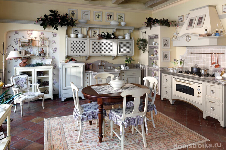 Кухня в стиле прованс с деревянной резной мебелью и цветочным рисунком на стенах и седушках стульев