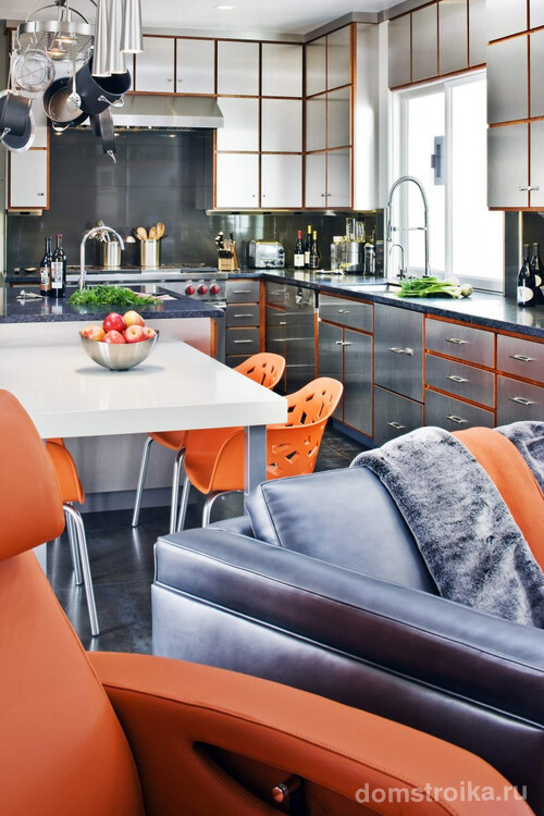 Оранжевый цвет объединяет пространство этой квартиры: он присутствует и на поверхностях шкафов, в оттенке лакированной древесины, и в обивке мягкой мебели, и ярких дизайнерских пластиковых стульях