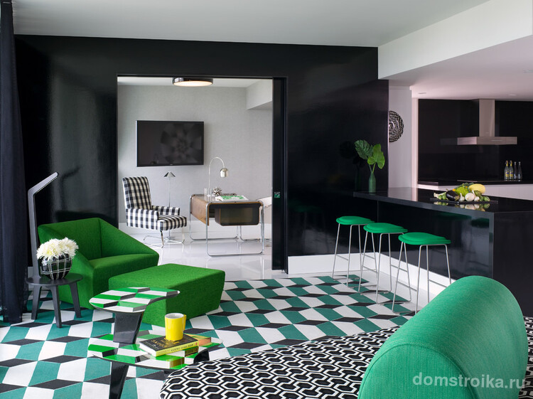 Встроенная барная стойка в интерьере большой кухни-студии в черно-белых тонах с яркими зелеными акцентами на мебели и элементах декора