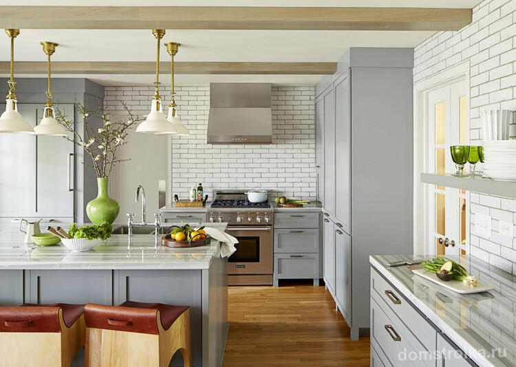 Просторная кухня-студия с белой кирпичной кладкой на стенах и яркими зелеными акцентами в интерьере