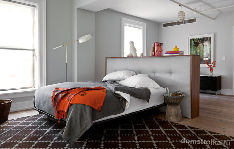 Индивидуально спроектированное и изготовленное массивное изголовье кровати, которое зрительно отделяет спальную от гостиной зоны