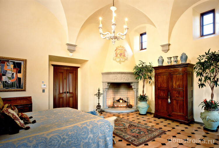 Красивый камин, украшенный лепниной, в интерьере спальни средиземноморского стиля
