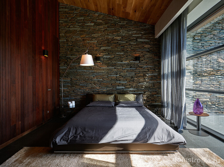 Спальня в стиле лофт с темно-коричневым ламинатом на одной стене и декоративным камнем на другой