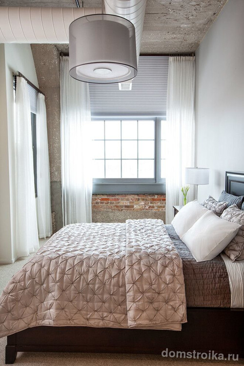 Светло-серые жалюзи и белая легкая тюль хорошо сочетаются в небольшой спальне индустриального стиля