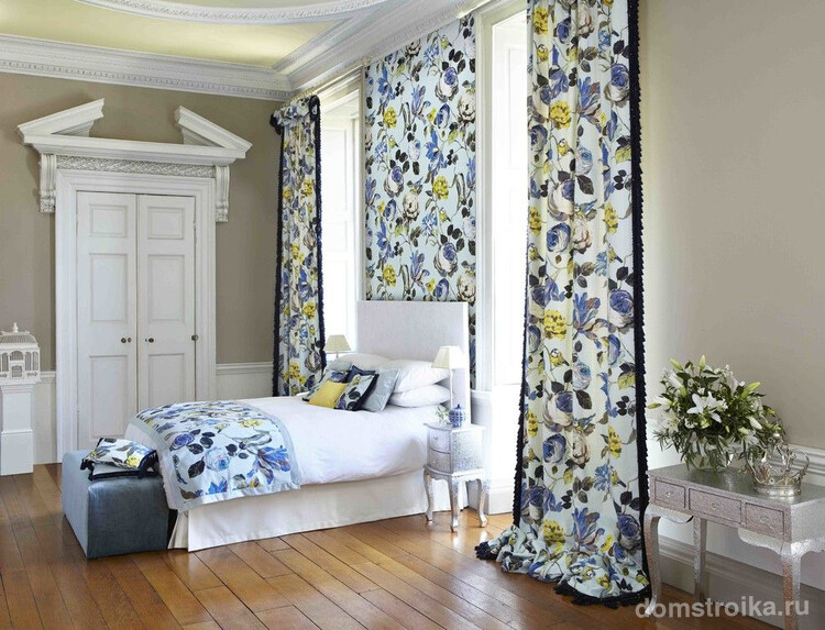 Анлийский стиль в оформлении спальни с цветными шторами, которые поддержаны вставкой из обоев с тем же рисунком и таким же покрывалом