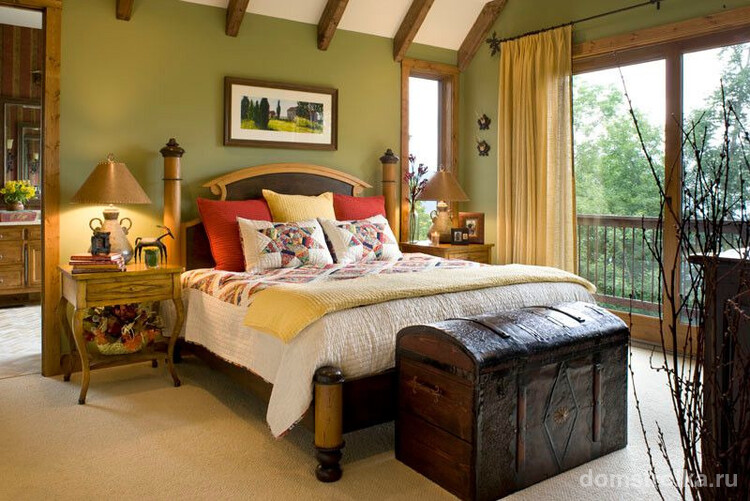 Текстильные элементы на кровати в технике пэчворк, французский пейзаж в деревянном обрамлении, живые цветы и другие милые мелочи для интерьера спальни в деревенском стиле прованс