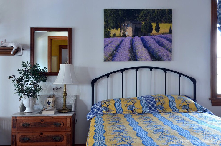 Изображение лавандовых полей на картине в простом интерьере спальни