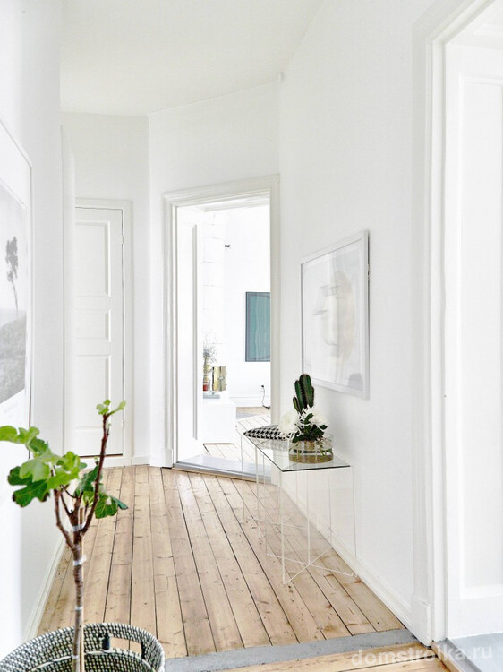 Маленький коридор в белых тонах со светлым деревянным полом. Пространство в таких условиях в разы визуально увеличивается
