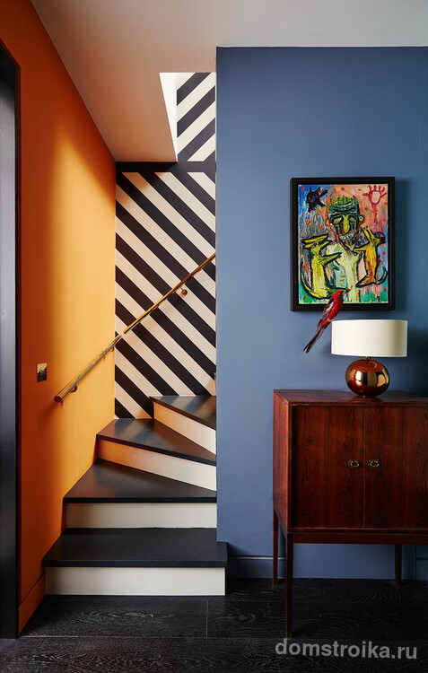 Разноцветные окрашенные стены и уводящая взгляд иллюзия, созданная полосатыми обоями над лестницей