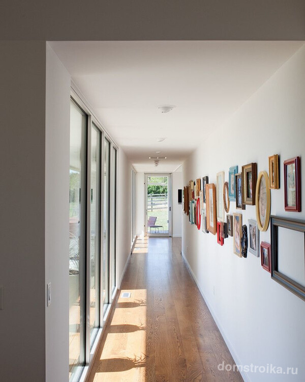 Длинный коридор частного дома с панорамными окнами и мини-галереей