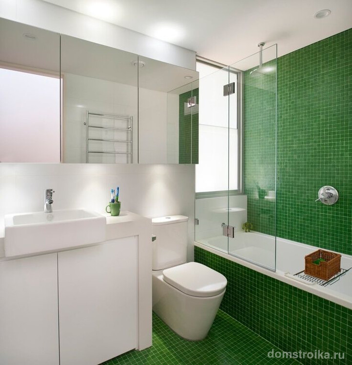 Свежая комната с отделкой одной из стен и пола зеленой мелкой плиткой и практически незаметной в интерьере стеклянной шторкой для ванной