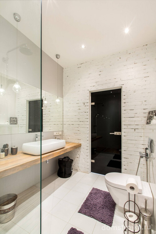 Совмещенный санузел в современном стиле с душевой вместо ванны. Примечателен здесь выбор отделки: на одной стене сохранена открытая кирпичная кладка