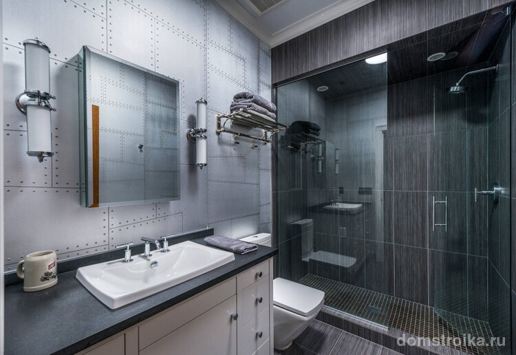 Очень мужской дизайн серой ванной комнаты, чрезмерную строгость в котором нивелирует сюжет в рисунке акцентной стены на тему клепанных листов металла