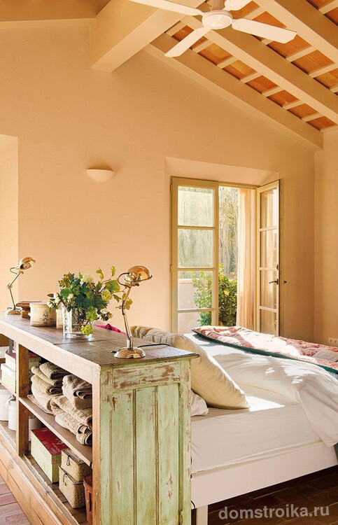 Состаренная тумба и стены нежно-персикового цвета в спальне