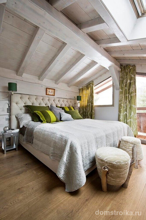 Скошенное мансардное окно с портьерами оливкового цвета в небольшой уютной спальне