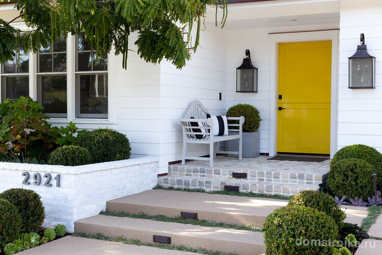 Традиционный экстерьер частного дома с особенностью в виде глянцевой пластиковой входной двери насыщенного желтого цвета с надежным замком