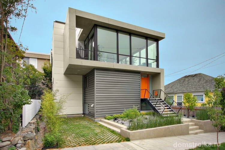 Стильный частный дом с балконом молочно-серого цвета с ярко-оранжевой дверью