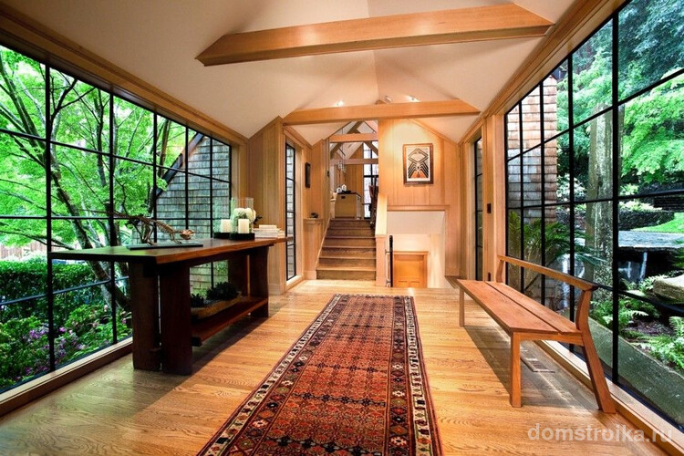 Просторный холл с панорамными окнами и деревянной мебелью