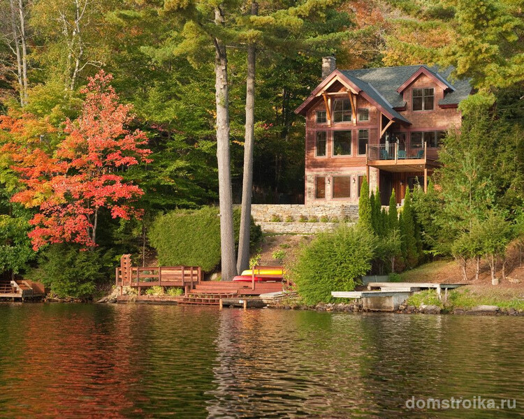 Великолепный вид каркасного дома на фоне леса и озера