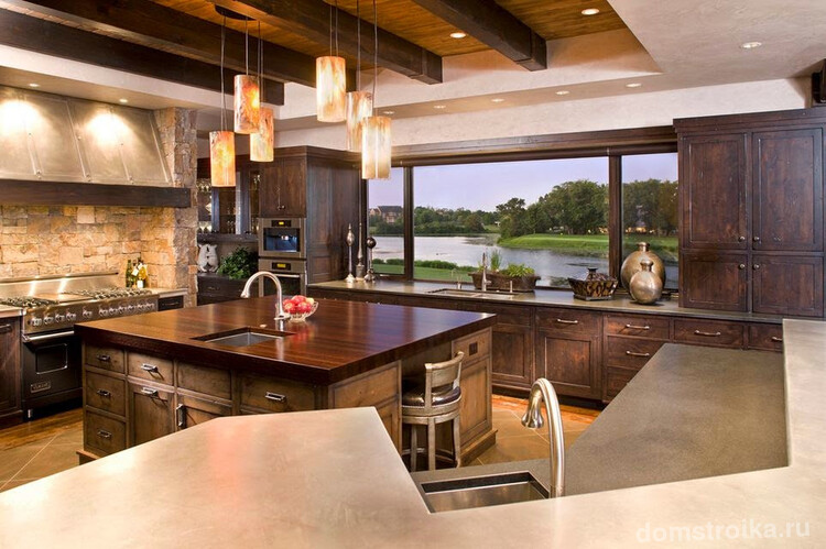 Роскошная кухня с деревянным кухонным гарнитуром и панорамным окном на всю стену, оформленным подоконником-столешницей